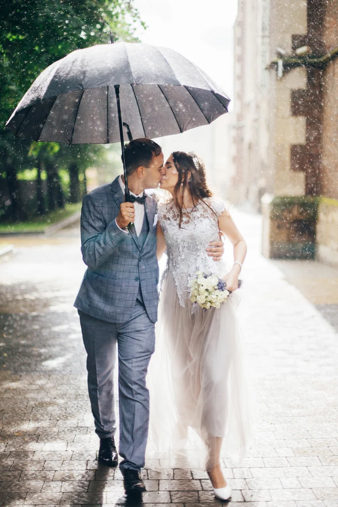 Des mariés marchent sous la pluie avec un parapluie : un très beau cadre pour un film de mariage